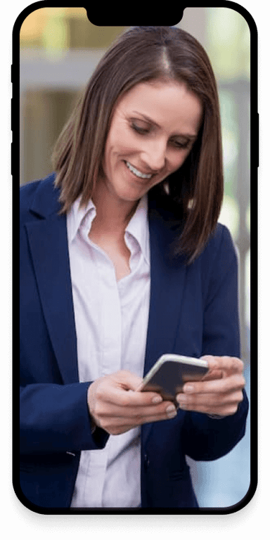 A business woman, smiling and looking down at her cellphone.
