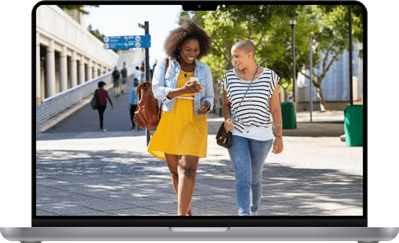 Two women walking and smiling at a phone.