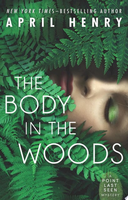 The cover features lush green ferns partially obscuring a face, creating a sense of mystery and suspense. The predominantly green palette evokes the natural setting of the woods.