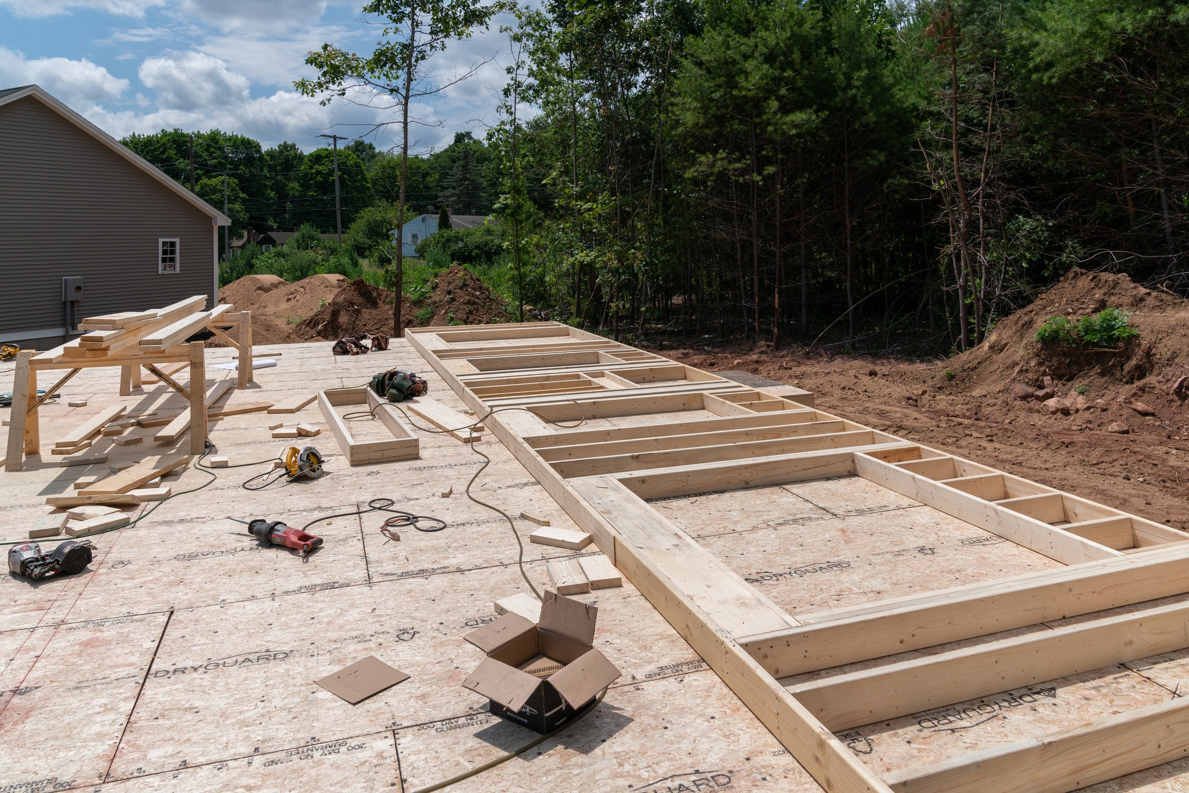 Residential construction site with lumber scraps and framing tools scattered across DryGuard subfloor