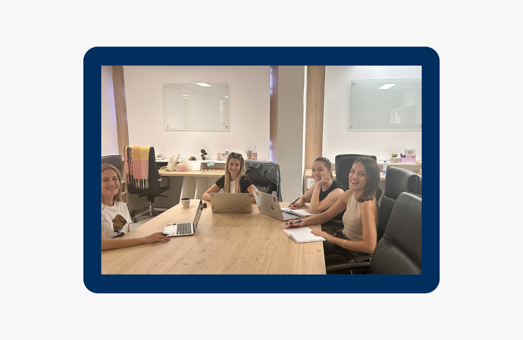 smiling customer service team members collaborating at a conference table, working on laptops and taking notes in a bright and modern office environment, showcasing teamwork and dedication to client support