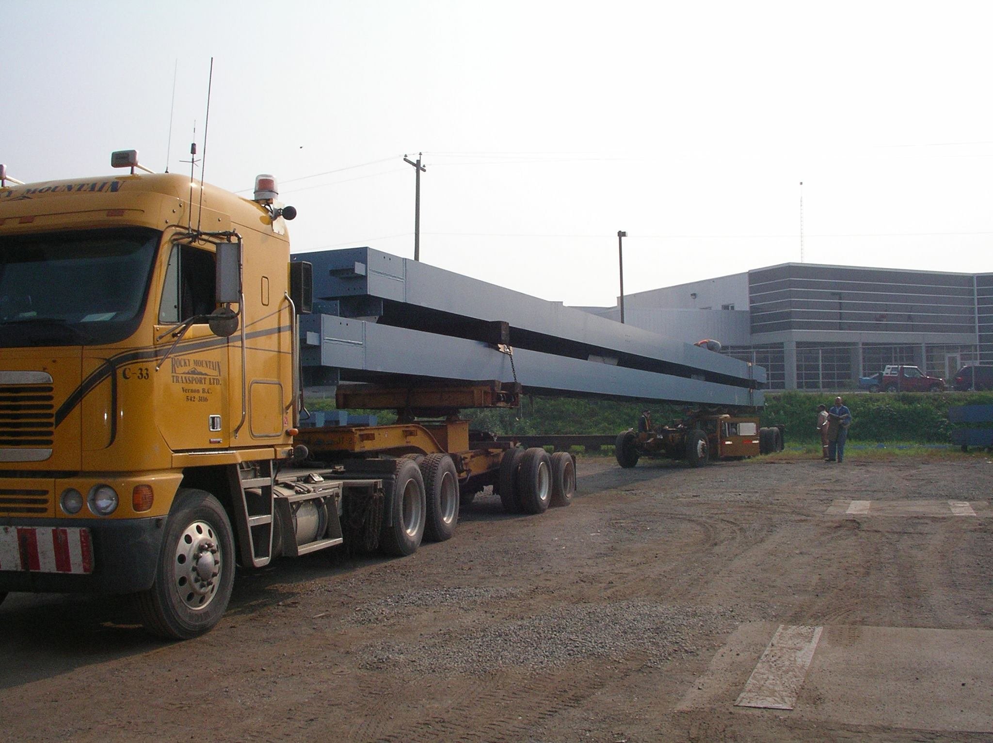Cabover truck loaded with long structural steel beams on an extendable trailer