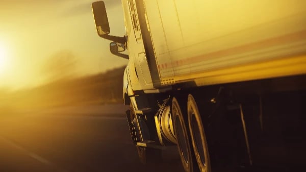 Motion-blurred close-up of trailer wheels and chassis at golden hour