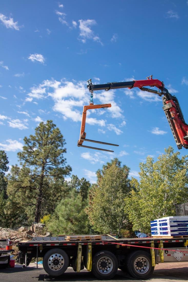 Flatbed trucking services - crane loading equipment onto truck