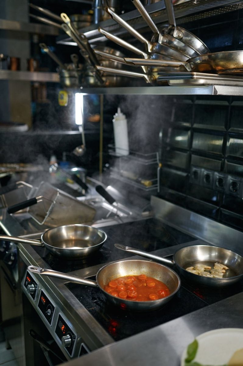 Commercial kitchen equipment steaming pans on stove