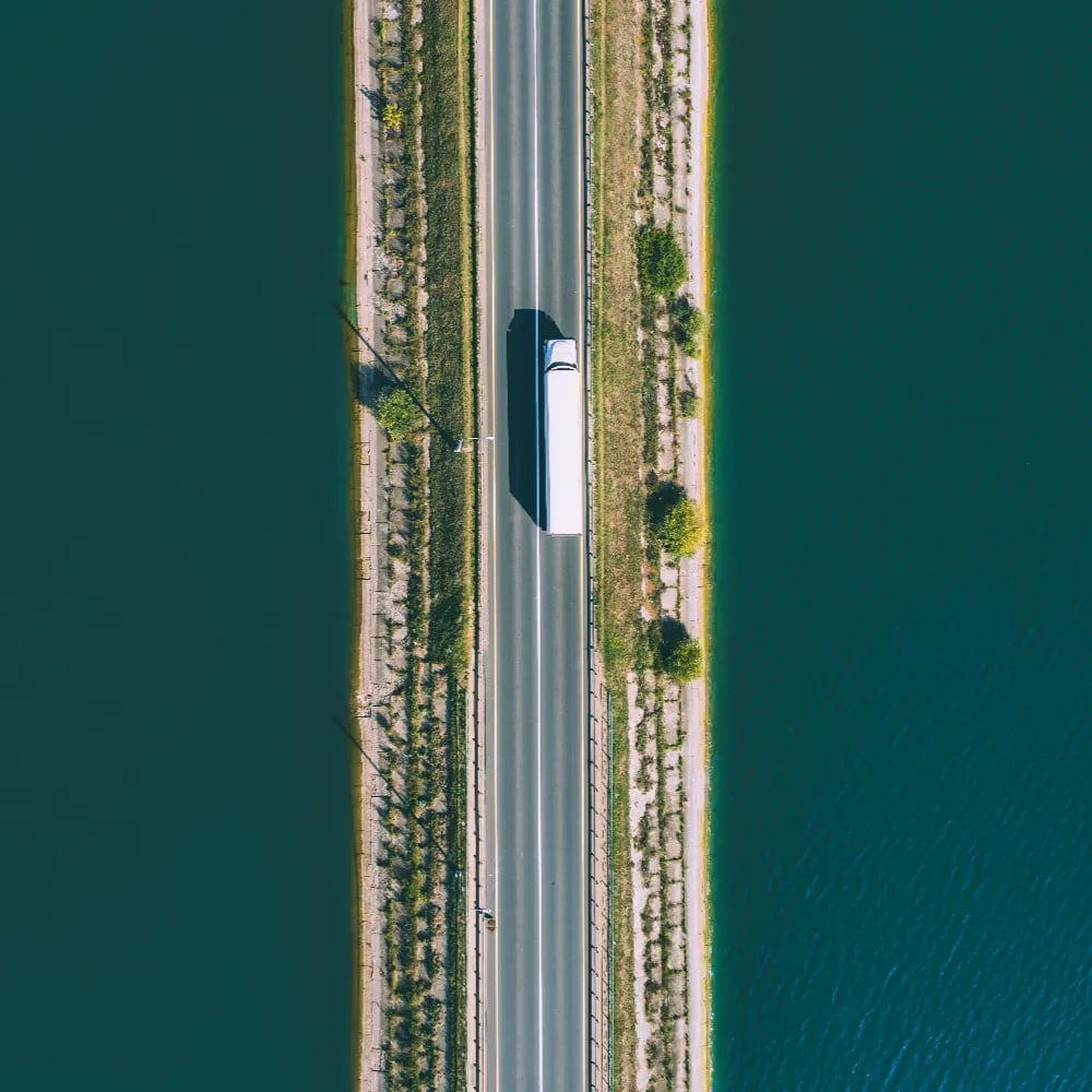 dry-van-aerial Aerial view of a truck crossing a narrow causeway between blue water