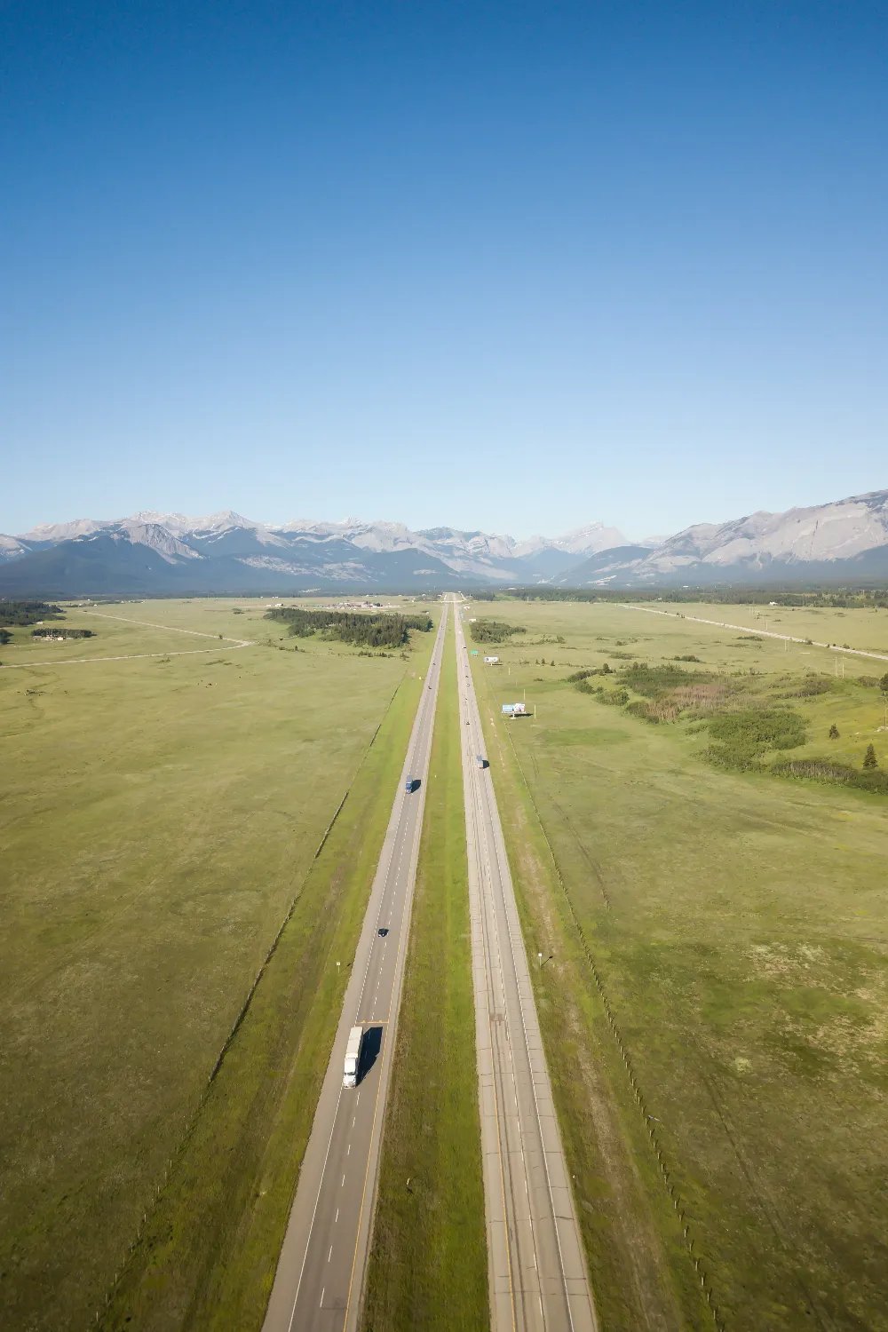 Aerial view of a divided highway crossing open prairie toward the Rocky Mountains