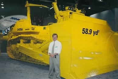 Fortress Forwarders founder beside a Komatsu D475A dozer with a 58.9 cubic yard blade at an equipment show