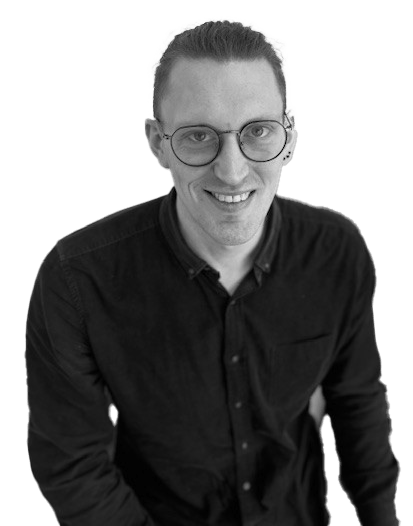 Nick Morrison - The Audiology Place portrait of a smiling man with round glasses wearing a black button down shirt in a monochrome photo nick morrison independent audiologist epping the audiology place