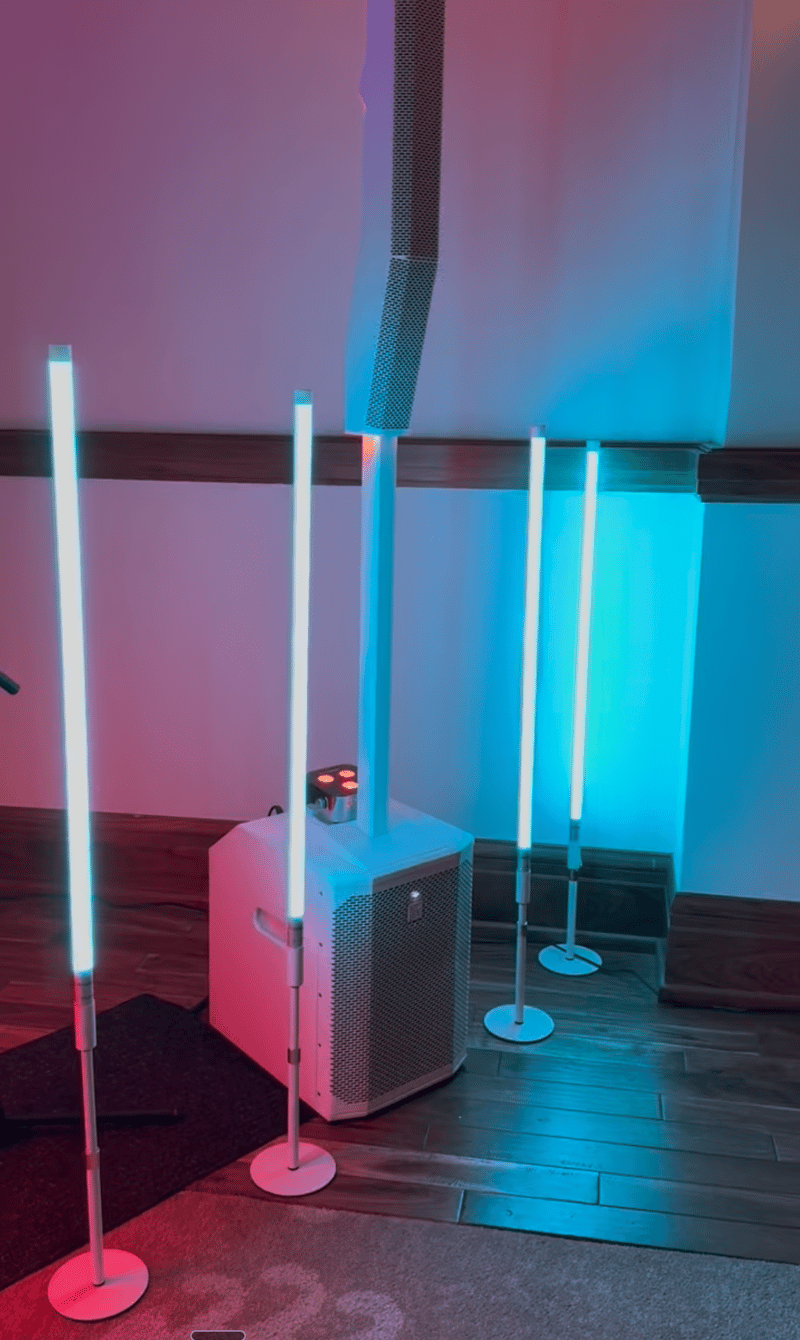 Eight Firefly GloTube LED light tubes standing in a reception space, lit in pink and teal