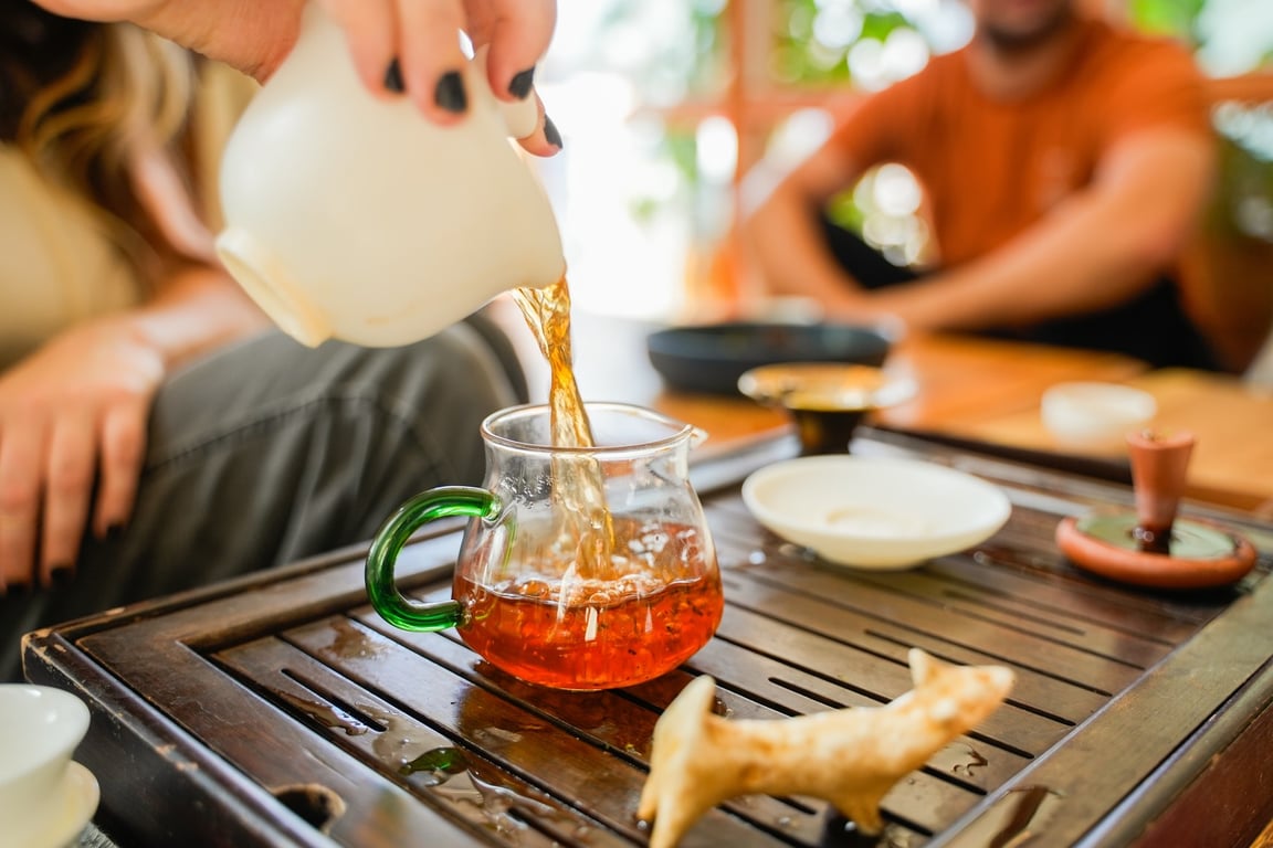 Two students pouring tea in plant-filled studio