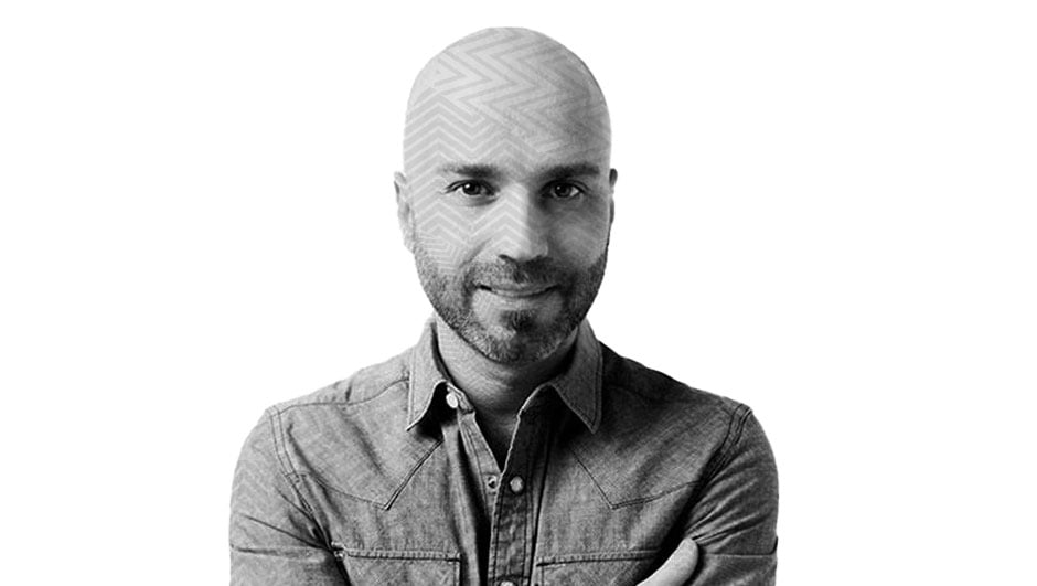 Fotografía con efecto blanco y negro y un patrón de líneas transparentes sobre el rostro Gabriel Bauducco, un hombre de mediana edad con calvicie y barba en su rostro, aparece sonriendo, cruzando los brazos, utilizando una camisa.