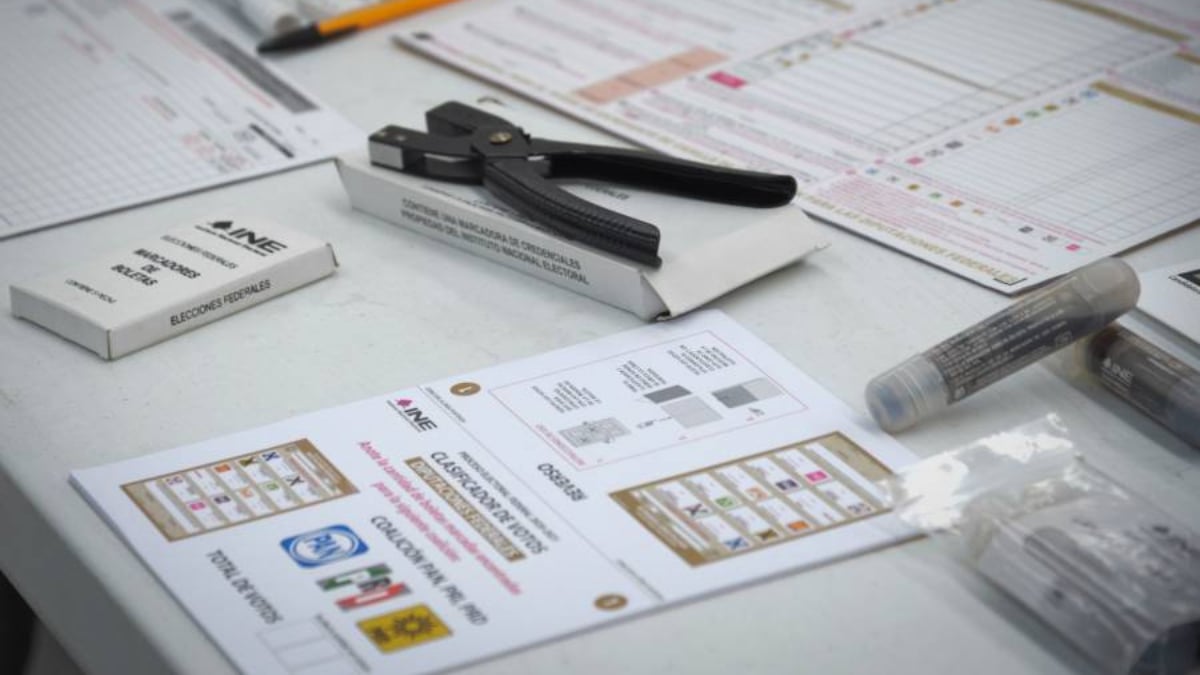 Fotografía que muestra diversos materiales electorales que estarán a disposición de las personas con discapacidad para que puedan emitir su sufragio el domingo. En un primer plano se ve la boleta electoral con una mascarilla braille. Un poco más arriba está un clip que permite sujetar la boleta para que puedan apoyarse con más facilidad al momento de votar.