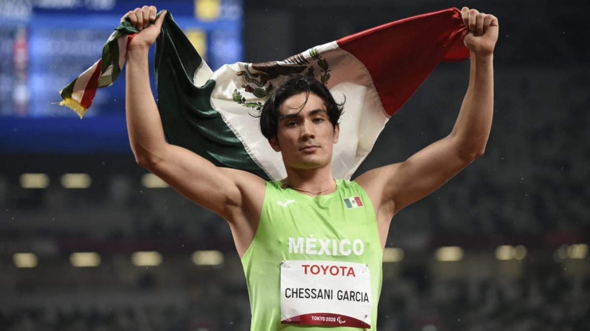 Rodolfo Chessani sosteniendo la bandera de México atrás de su cabeza.