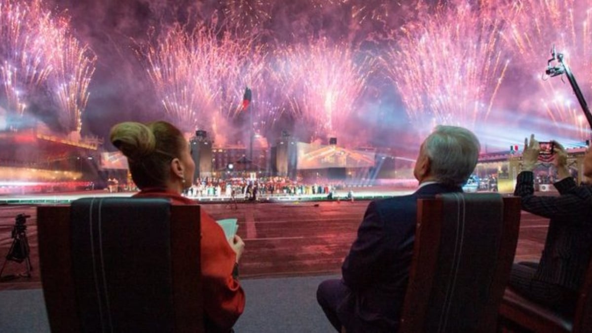 Dos personas adultas mayores sentadas de espaldas observan un espectáculo de fuegos artificiales en el zócalo de ciudad de México durante la conmemoración del bicentenario de la consumación de la independencia. La pareja observa el espectáculo desde Palacio Nacional.