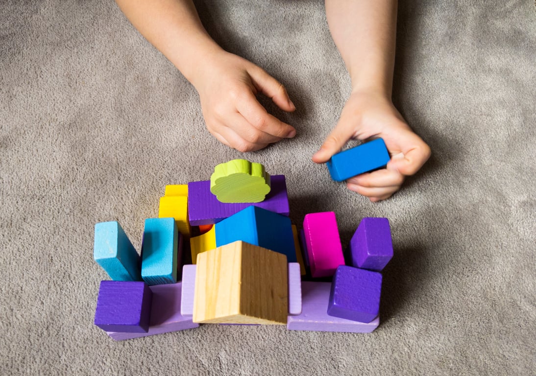 Niño jugando con bloques de madera de diferentes colores.