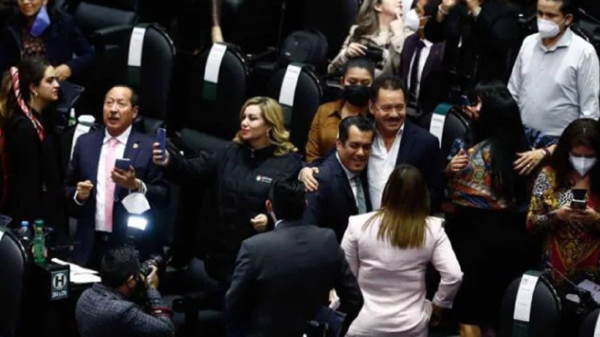 Fotografía de un grupo de legisladores y legisladoras de Morena entre las curules de San Lázaro, de pie, se abrazan, sonríen y algunos usan su celular tras la votación para poner topes a los donativos a las organizaciones de la sociedad civil.