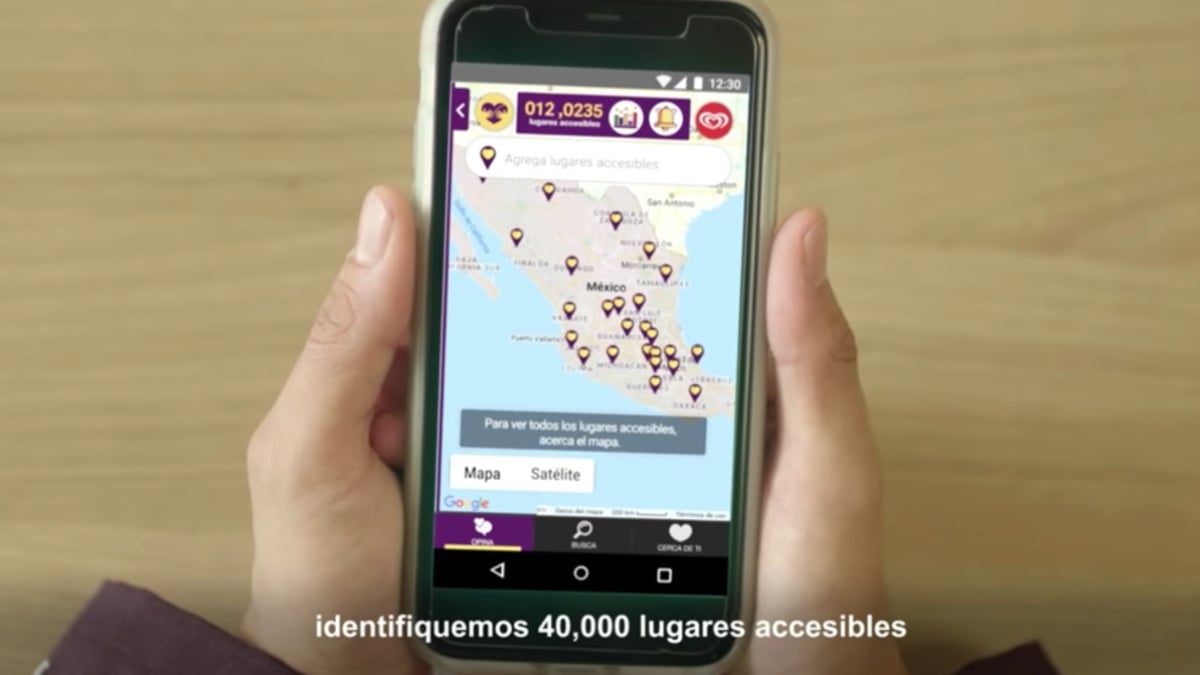 Fotografía de unas manos que sostienen un celular y se ven los dedos pulgares. En la pantalla del dispositivo hay un mapa de México con varios globos de localización. En la parte inferior, en letras blancas dice identifiquemos 40 mil lugares accesibles.