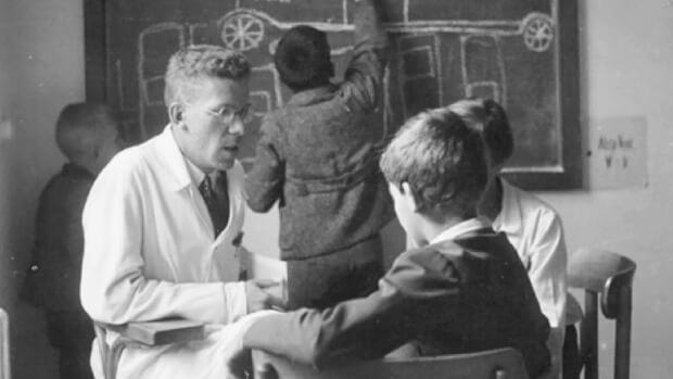 Hans Asperger conversando con un niño en lo que parece un aula de clases.