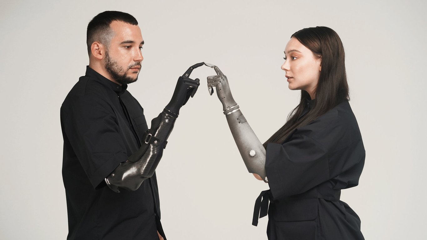 Dos personas cara a cara con prótesis de brazo inteligentes.