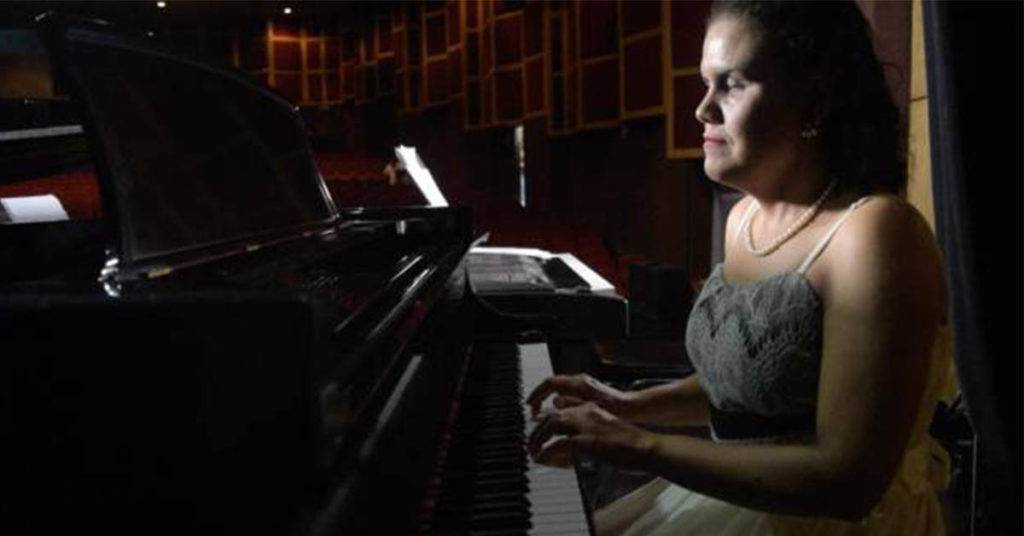 Mujer con discapacidad visual tocando las teclas de un piano.