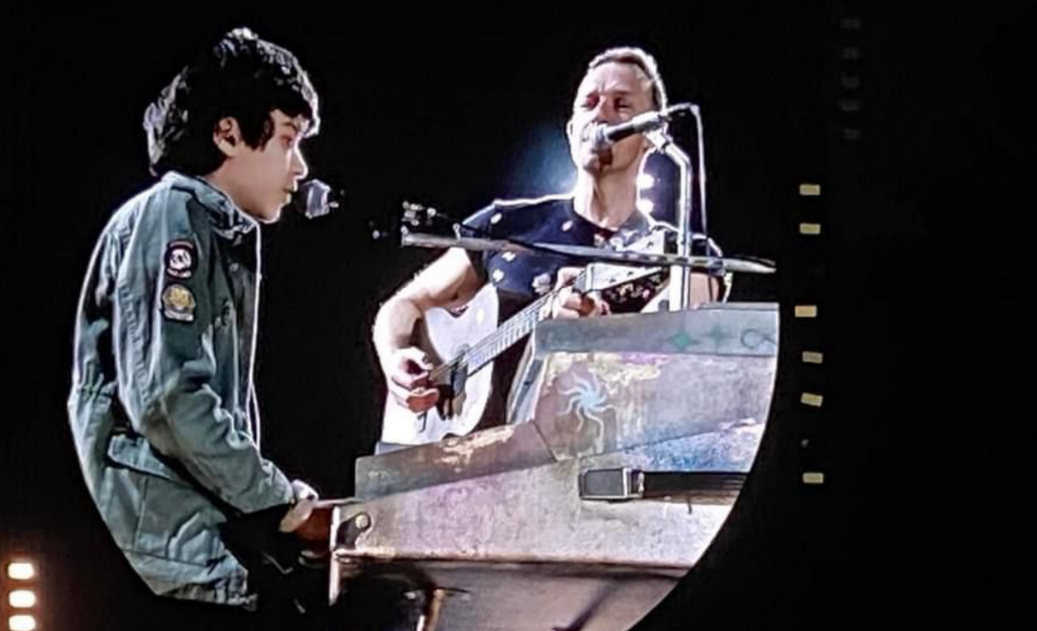 Pantalla del concierto de Coldplay que proyecta un niño tocando el piano junto al vocalista de la banda Chris Martin