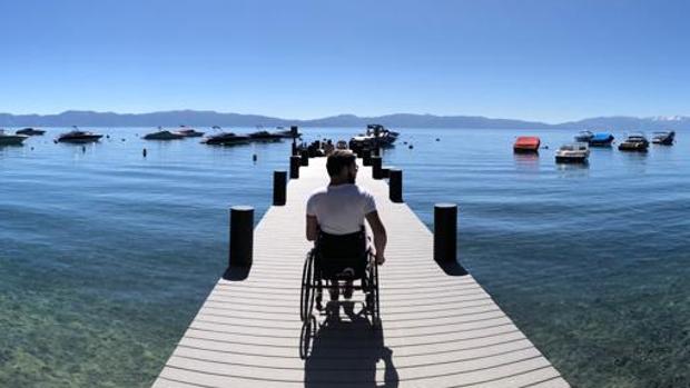 Usuaria de silla de ruedas en un muelle frente a un lago.