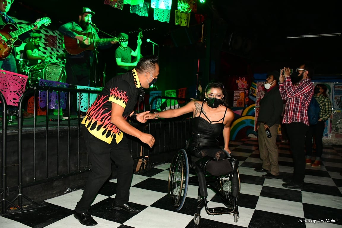 Usuaria en silla de ruedas bailando salsa con una persona sin discapacidad motriz.