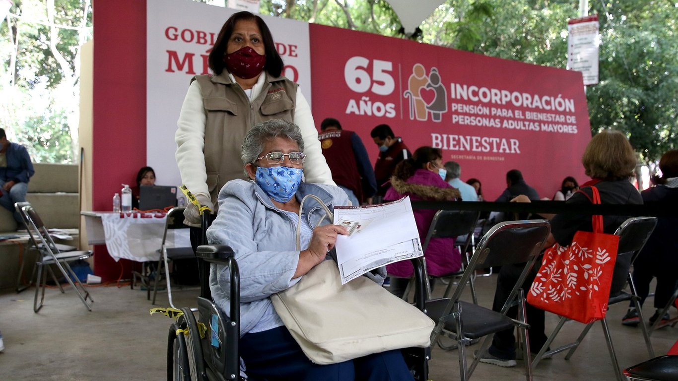 Usuaria de silla de ruedas sosteniendo su boleta de registro en un módulo para la pensión del bienestar.