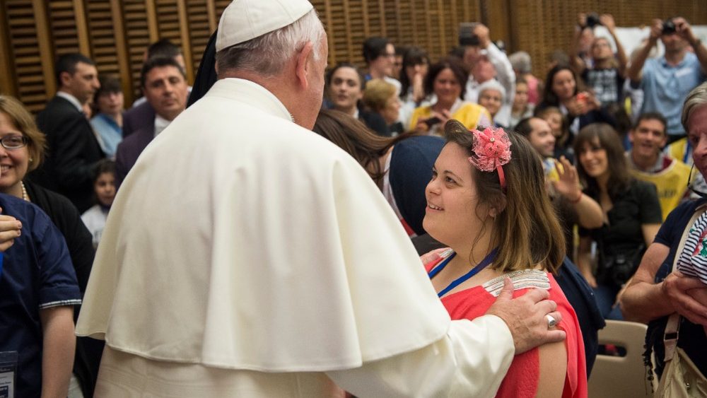 Papa dando la bendición a una niña con síndrome de Down.