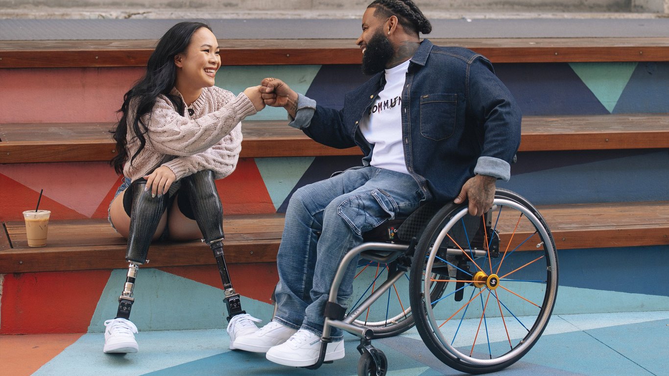 Usuario de silla de ruedas y joven mujer con prótesis en ambos pies utilizando el modelo de tenis Fit to Fit de la marca Reebok.