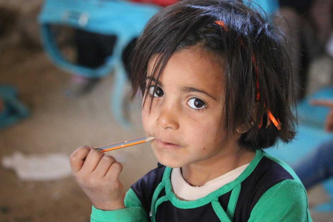 Niña mordiendo un lápiz.