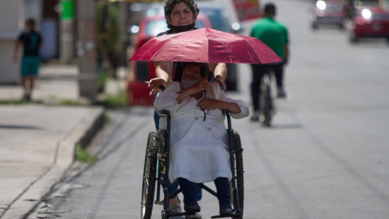Usuario en silla de ruedas utiliza un paraguas para cubrirse del sol.