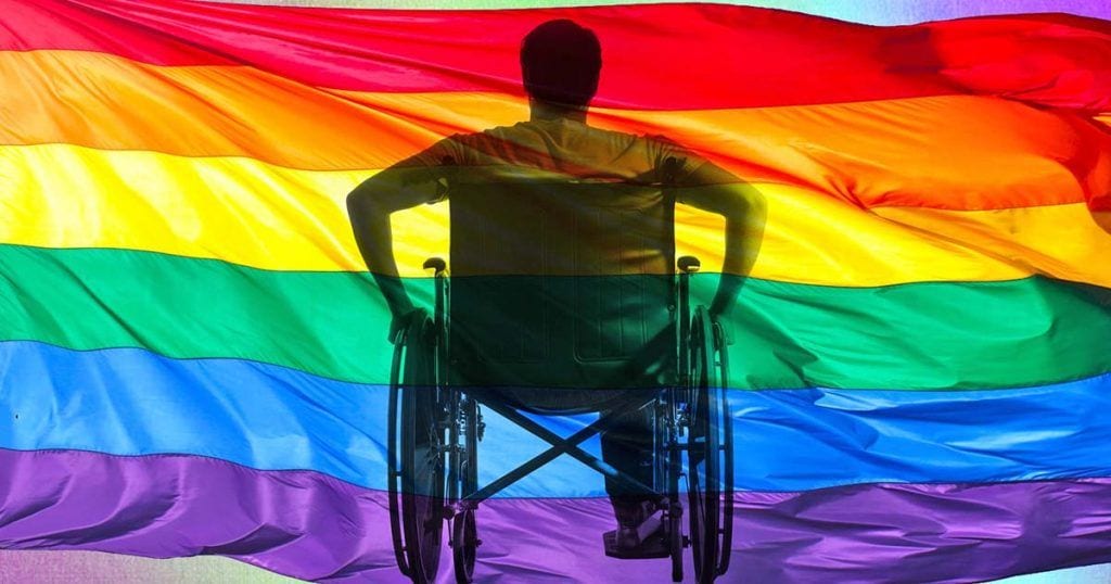 Usuario en silla de ruedas frente a una bandera LGBT
