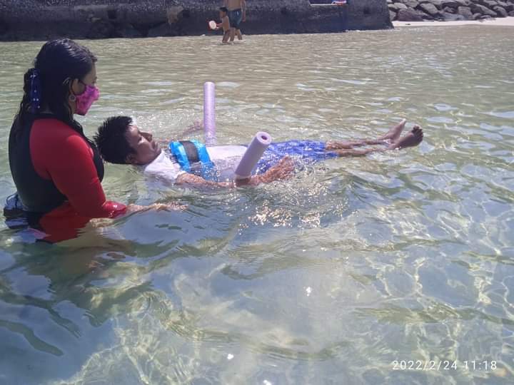 Persona con discapacidad motriz recostada en la playa.