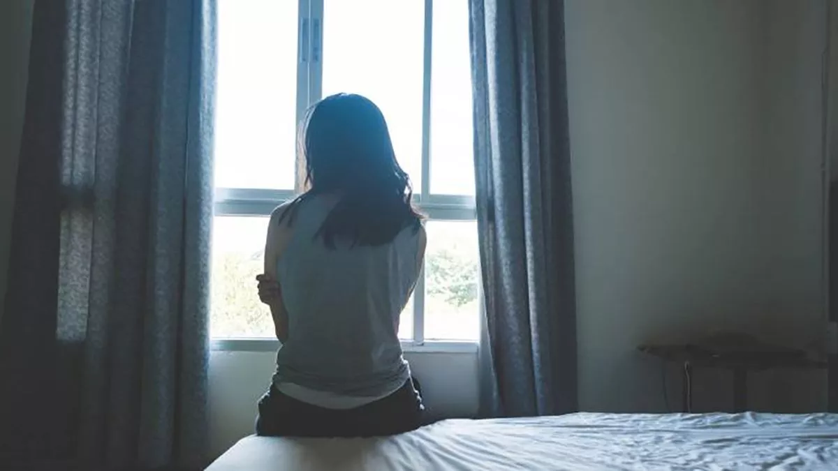 Mujer sentada frente a una ventana.