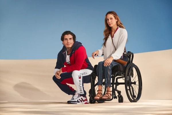 Dos modelos sobre una duna de arena, la mujer es usuaria de silla de ruedas.