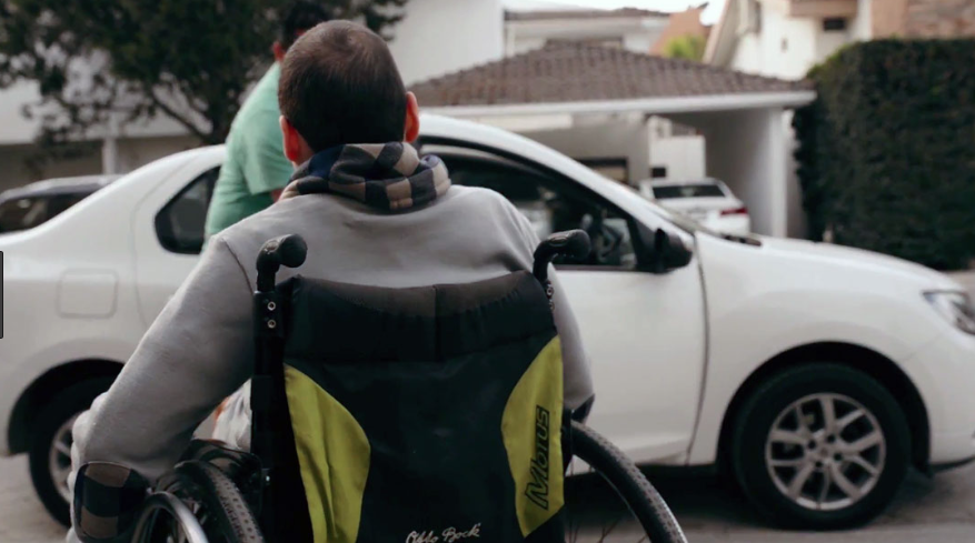 Usuario de silla de ruedas frente a un automóvil.