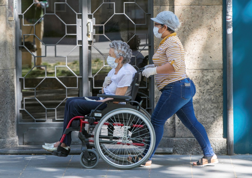 Cuidadora de una usuaria en silla de ruedas por la calle.