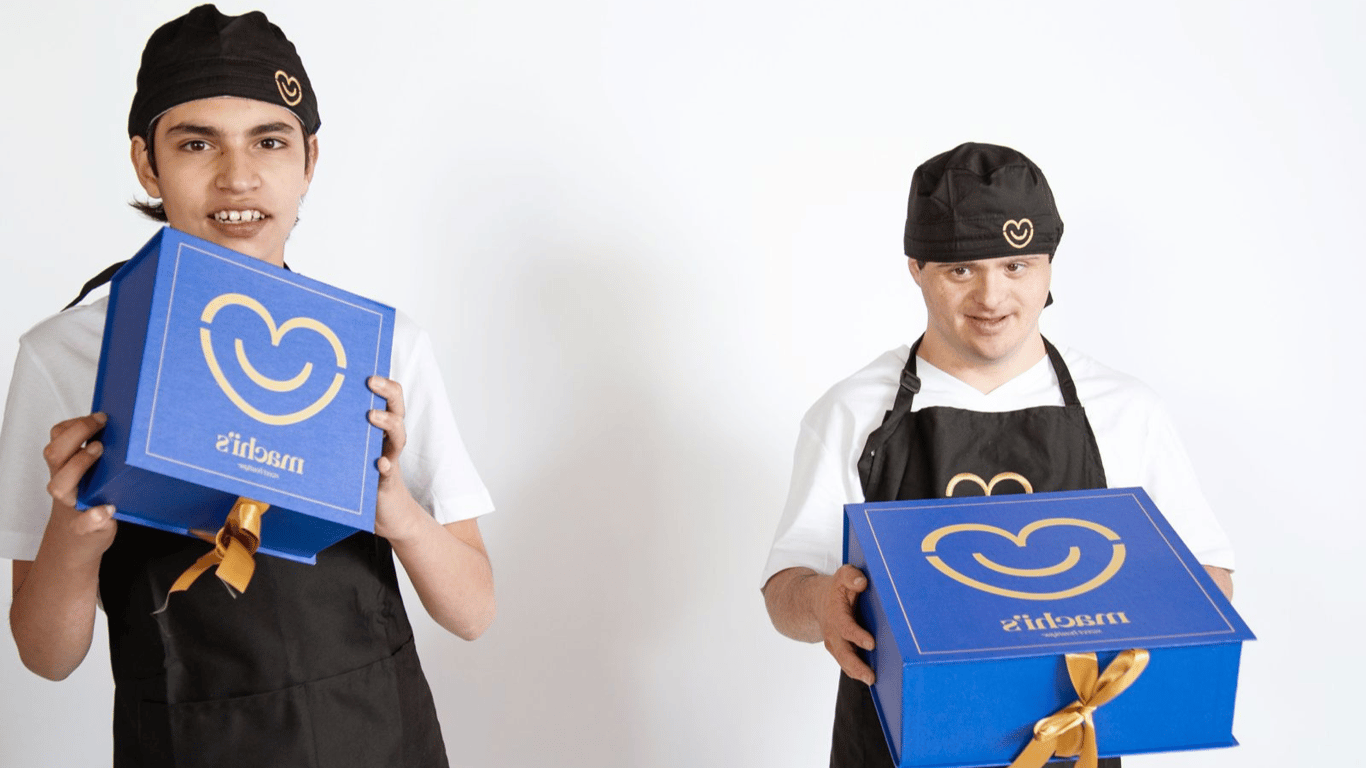 Juan y Marcelo sosteniendo cajas azules de la panadería Machi's