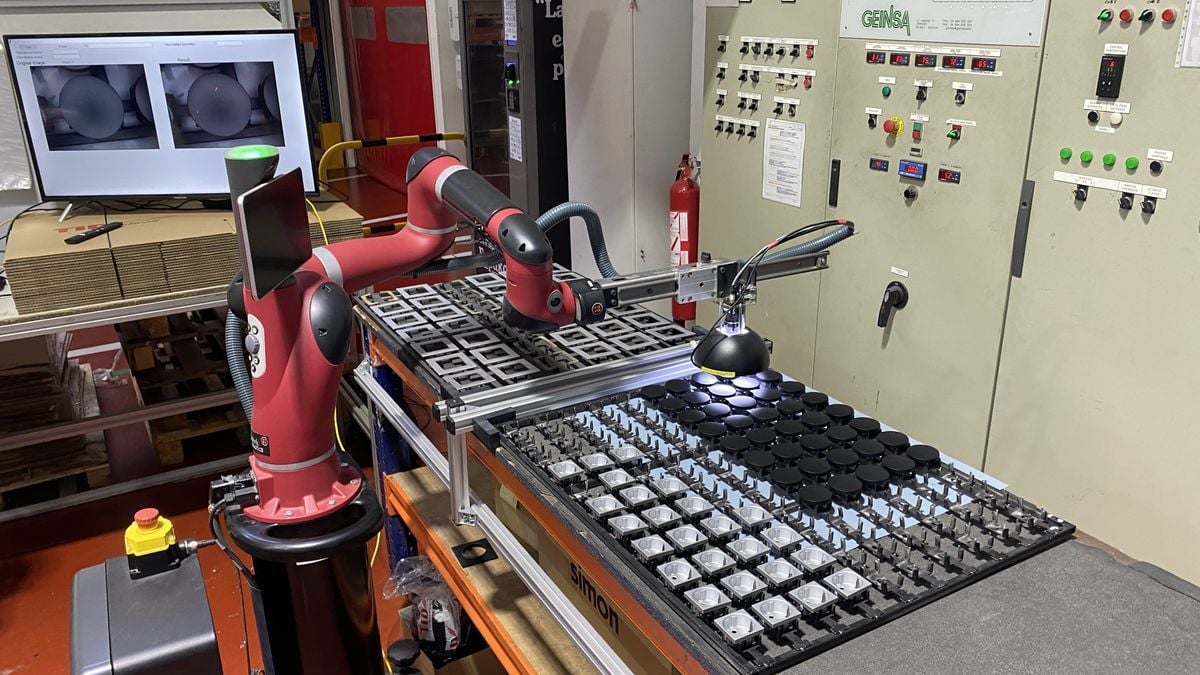 Brazo robot colocando piezas en un teclado.