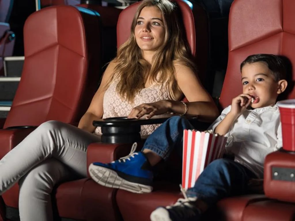 Madre con su hijo en las butacas de un teatro.