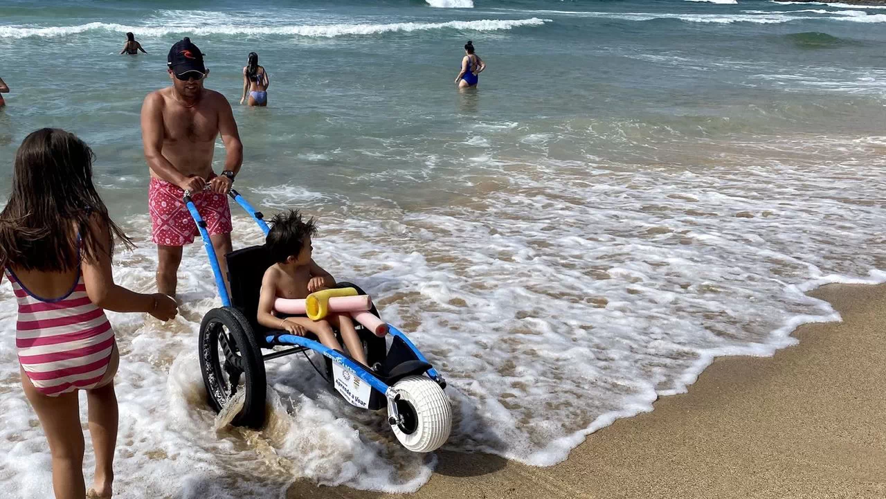 Niño con discapacidad con una silla anfibia dentro del mar.