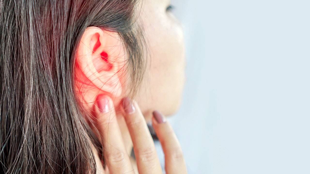 Mujer tocando con dolor su oído rojizo