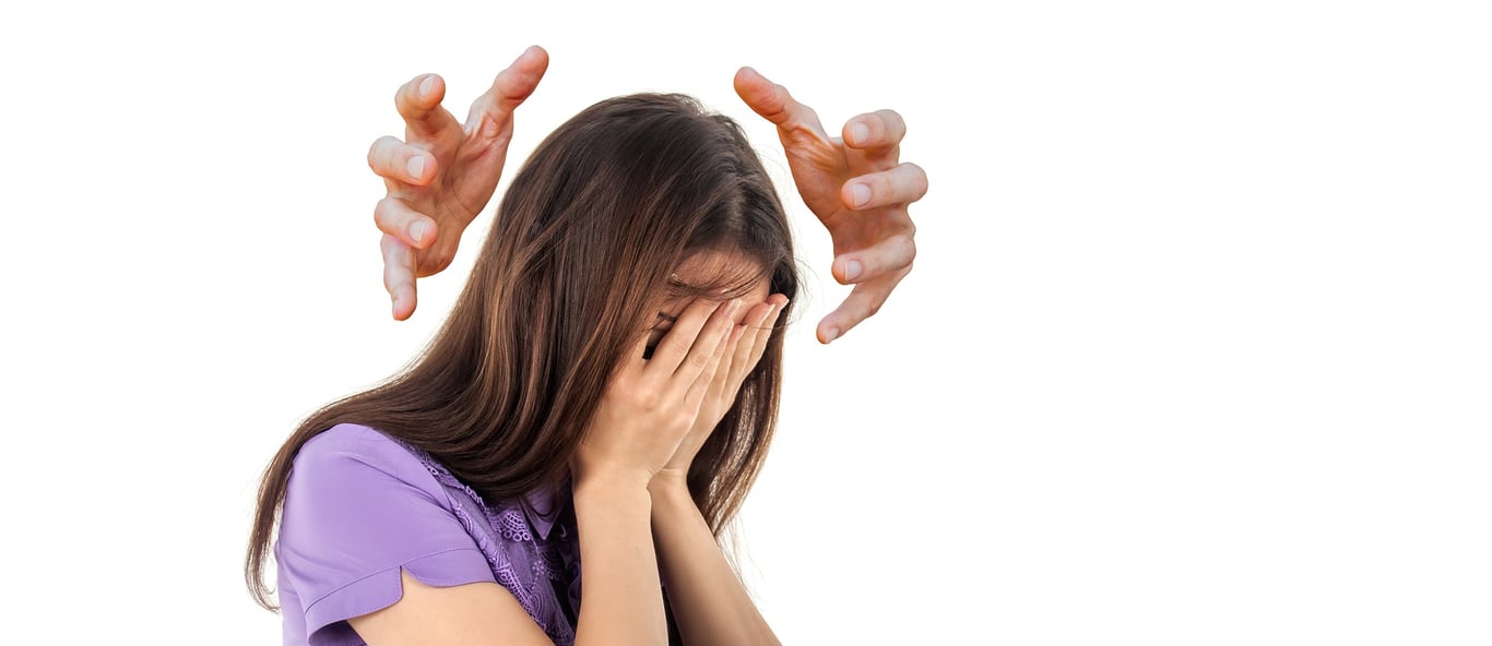 Mujer con ambas manos sobre su rostro y otro par de manos sobre su cabeza indicando problemas de salud mental.
