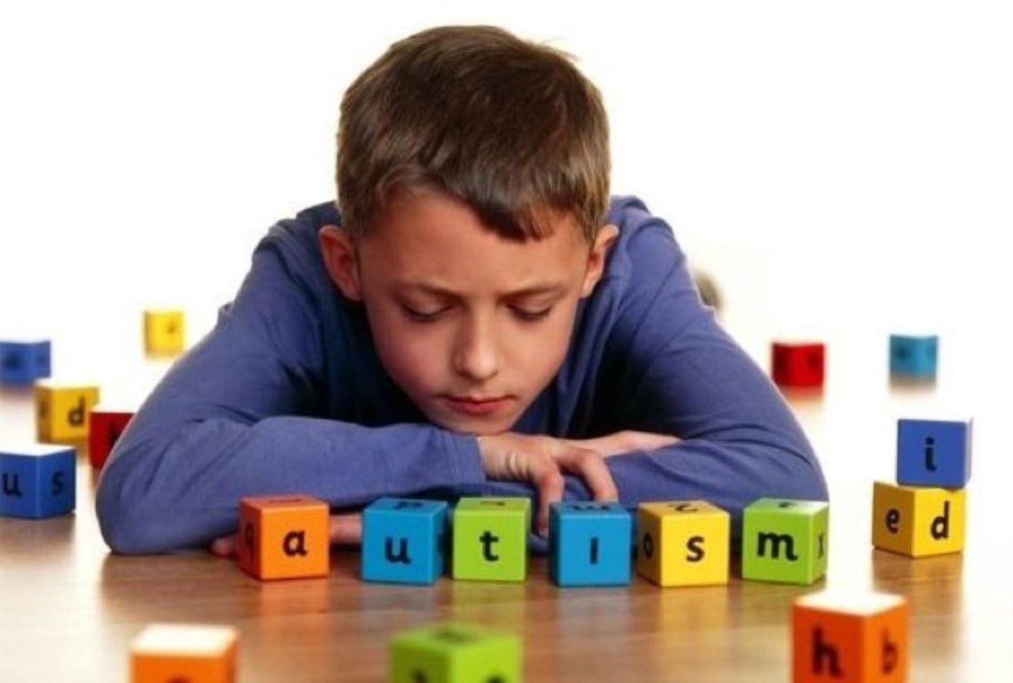 Niño con autismo jugando con cubos de letras de diferentes colores.