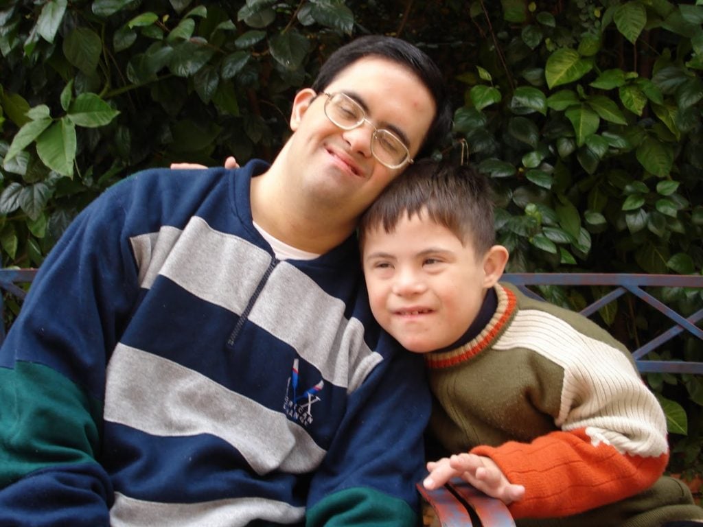 Adulto con síndrome de Down abrazando a un niño con la misma condición.