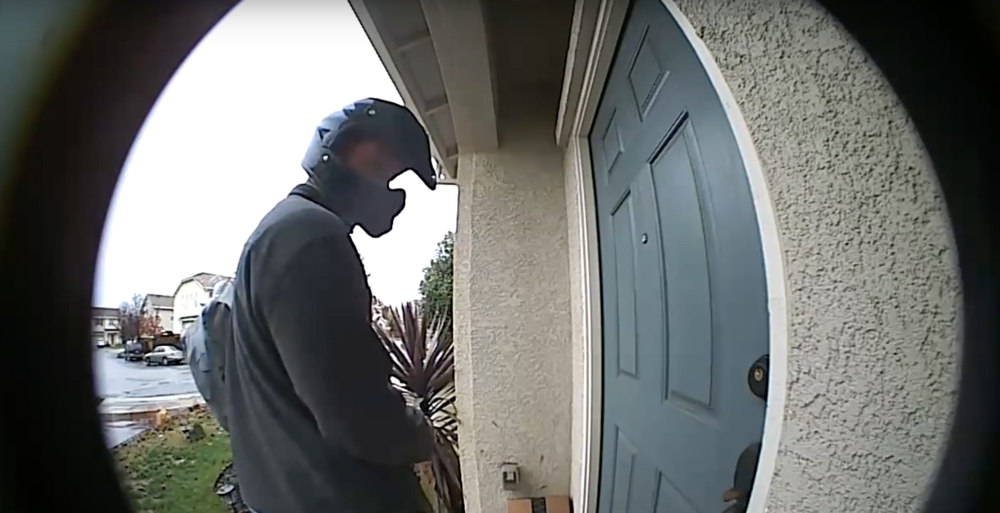 Repartidor frente a la puerta de una casa capturado a través de la cámara de un videotimbre