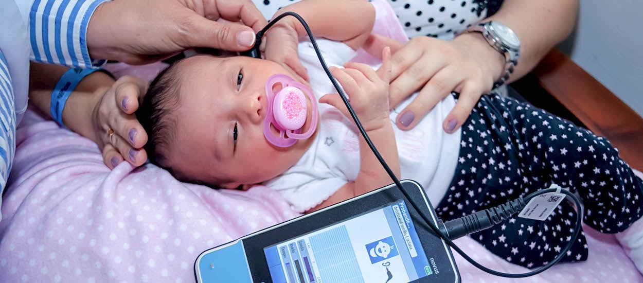 Bebé recién nacido al que un doctor le realiza un tamizaje auditivo neonatal
