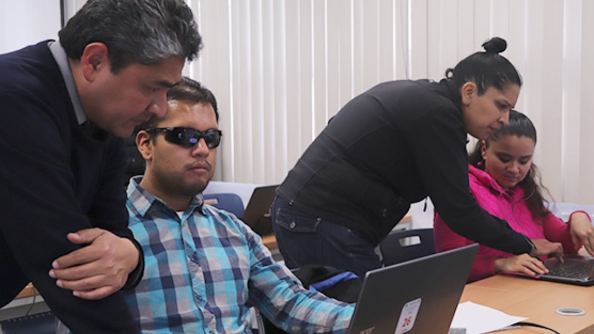 Dos personas con discapacidad visual tomando un curso de cómputo.